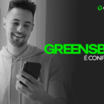 Greenbets é Confiável? Imagem preta e branca no fundo de um homem de casaco, sorrindo e com celular na mão