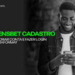Imagem de fundo em preto e branco usando uma jaqueta jeans e sorrindo olhando para o celular. Cadastro Greensbet: Como Criar Conta e Fazer Login na Plataforma?